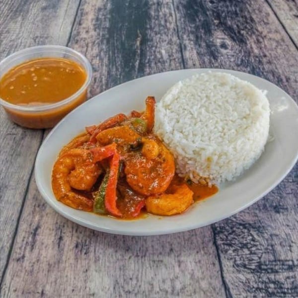 Shrimp and bell peppers in a rich orange sauce, served with white rice and a side of sauce.